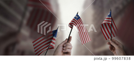 A group of people holding small flags of the Liberia in their hands A group of people holding small flags of the Liberia in their hands 99607838