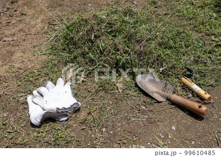 スコップと軍手と雑草の山 99610485