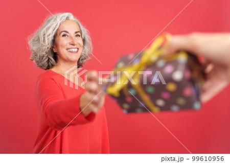 A happy mature woman receiving a gift 99610956
