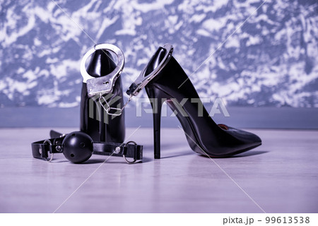 Adult sex games. Kinky lifestyle. Pair of black high-heeled shoes with gag ball and handcuffs. Bdsm outfit Adult sex games. Kinky lifestyle. Pair of black high-heeled shoes with gag ball and handcuffs. Bdsm outfit 99613538