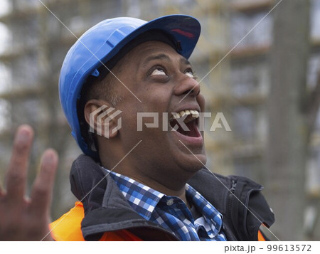 Close up portrait of a laughing Somali civil engineer wearing protective vest and helmet at work on construction site 99613572