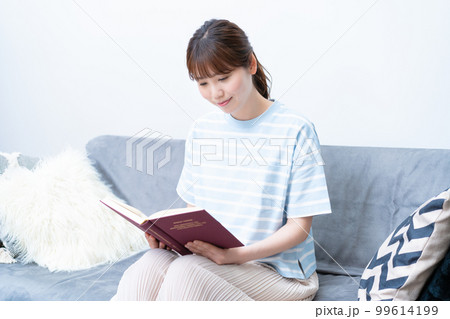 ソファで読書する若い女性 ソファで読書する若い女性 99614199