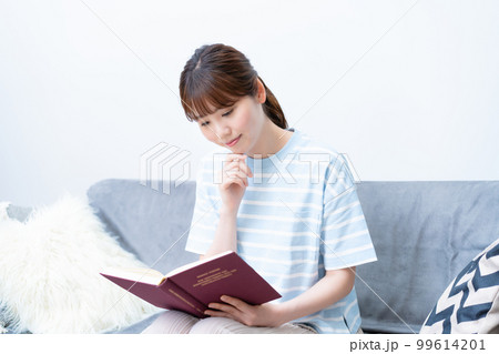 ソファで読書する若い女性 99614201