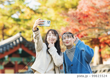 友達と秋の旅行に出かけてスマホで写真を撮る女性 友達と秋の旅行に出かけてスマホで写真を撮る女性 99615524