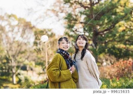 友達と公園を散策する女性 99615635