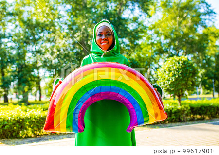 african woman in green hijab with bright makeup with rainbow air balloon in summer park outdoor 99617901