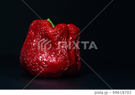 wrinkled old red sweet bell pepper on a dark black background close-up wrinkled old red sweet bell pepper on a dark black background close-up 99618702