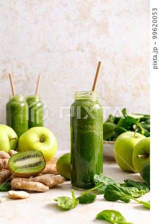 Smoothie. Healthy fresh raw detox spinach smoothie with green apple, kiwi and ginger in a bottles on a table. Healthy diet vegan food full of antioxidants Smoothie. Healthy fresh raw detox spinach smoothie with green apple, kiwi and ginger in a bottles on a table. Healthy diet vegan food full of antioxidants 99620053