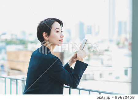 屋上でスマホを使うミドルの女性 99620459