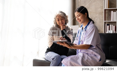 Nurse talking with a nursing home patient about his health. The nurse is making notes on a digital tablet 99621094