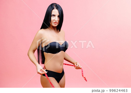 The girl taking measurements of her body isolated in studio on pink background. Close Up, exercise and workout results for healthy model The girl taking measurements of her body isolated in studio on pink background. Close Up, exercise and workout results for healthy model 99624463