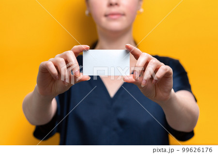 The woman holds a blank white card. Close up. Yellow background. Mock up The woman holds a blank white card. Close up. Yellow background. Mock up 99626176