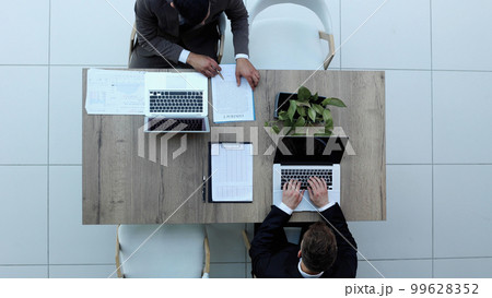 Two successful smiling businessmen are working on a laptop. view from above Two successful smiling businessmen are working on a laptop. view from above 99628352