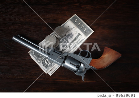 Old west revolver with bill and silver dollars 99629691