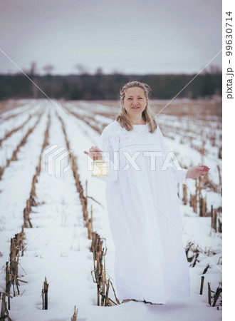Attractive woman in nightgown in the field in winter with hand lamp Attractive woman in nightgown in the field in winter with hand lamp 99630714