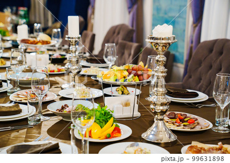 a large festive table with candles, snacks and tableware. a large festive table with candles, snacks and tableware. 99631898