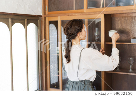 食器棚に食器をしまう女性 99632150