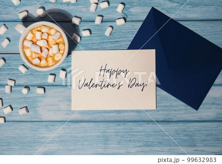 HAPPY VALENTINES DAY text Greeting card blue envelope with white cup of coffee and marshmallows on wooden blue background holiday 99632983