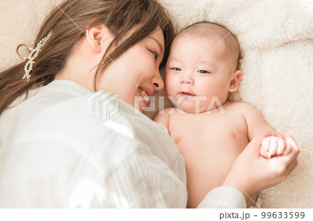 布団の上でリラックスする赤ちゃんと産後のママ（親子・出産・母子・産後・産褥期） 99633599