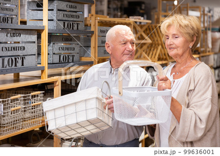 Mature married couple makes choice of buying a basket for country house 99636001