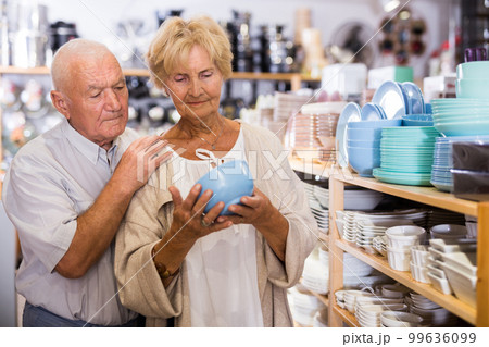 Portrait of an elderly couple in tableware store - making selection of new plates and cups Portrait of an elderly couple in tableware store - making selection of new plates and cups 99636099