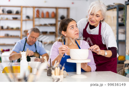 Potter woman in workshop gives modeling lesson Potter woman in workshop gives modeling lesson 99636149
