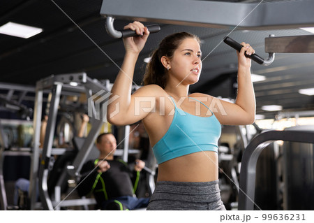 Young girl working out on lat pulldown lever machine 99636231
