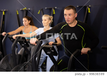 Sporty strong man using elliptical machine in gym 99636599