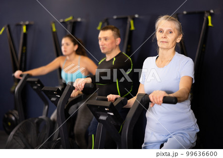 Group of people performs aerobic training workout cardio routine on spin bike 99636600