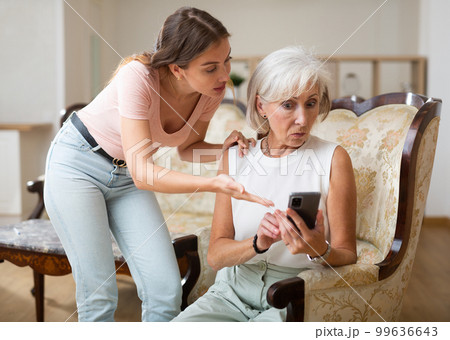 Mother and daughter using smartphone together at home 99636643