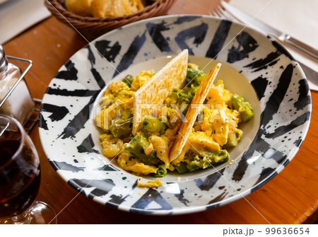 Scrambled eggs with asparagus and prawns at plate 99636654