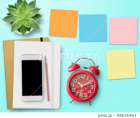 Blank notebook and red alarm clock on work space. Office desk for business concept. 99636963