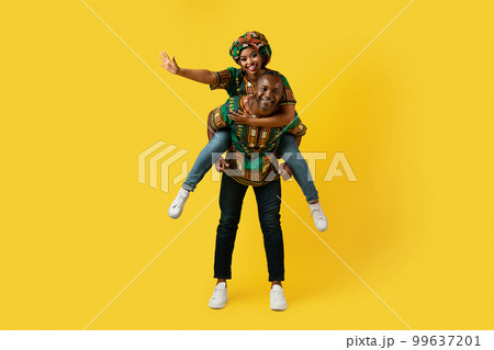 Happy black couple in traditional costumes posing on yellow 99637201