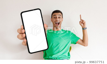 Great Offer. Excited Arab Guy Sitting In Chair And Holding Blank Smartphone 99637751