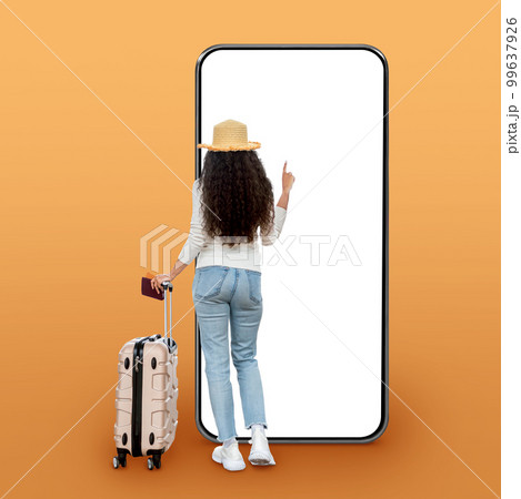 Brunette curly woman traveller checking flight info on big phone 99637926
