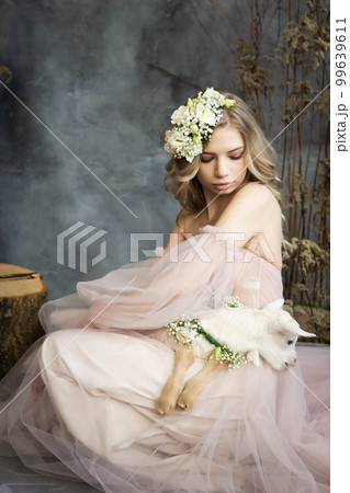 A young blonde woman in an airy pink dress with a white kid. Spring portrait of a woman. A young blonde woman in an airy pink dress with a white kid. Spring portrait of a woman. 99639611