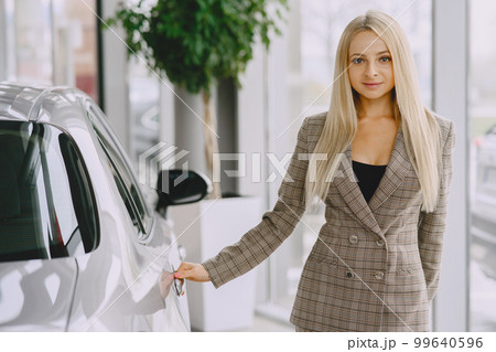 Lady in a car salon. Woman buying the car. Elegant woman in a brown suit. 99640596