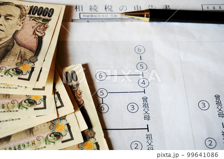 等親図と相続税申告書の上に置かれた一万円札とペン 99641086