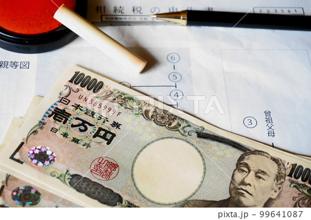 等親図と相続税申告書の上に置かれた印鑑とペン、一万円札 99641087