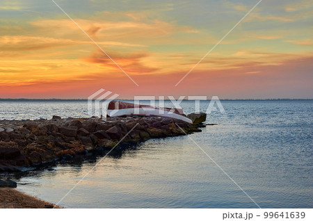 Old abandoned damaged fishing boat laying on the stone pier 99641639