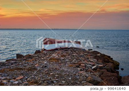 Old abandoned damaged fishing boat laying on the stone pier 99641640