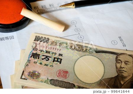 等親図と相続税申告書の上に置かれた印鑑とペン、一万円札 99641644