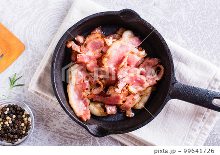 Fried bacon in a pan ready for dinner on the table. Top view. Closeup 99641726