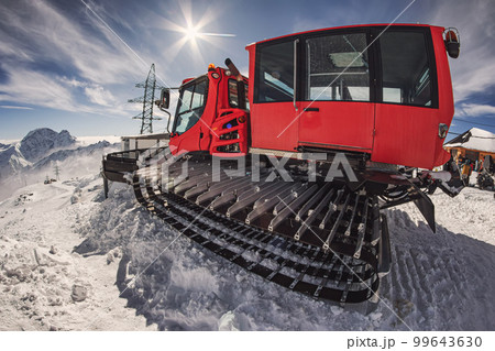 Snowcat stands in the highlands under the dazzling sunlight 99643630