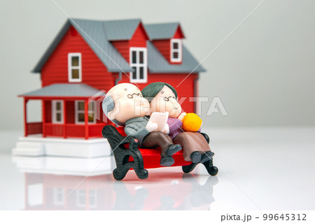 miniature people. a couple of retired people near the house model on a white background. 99645312