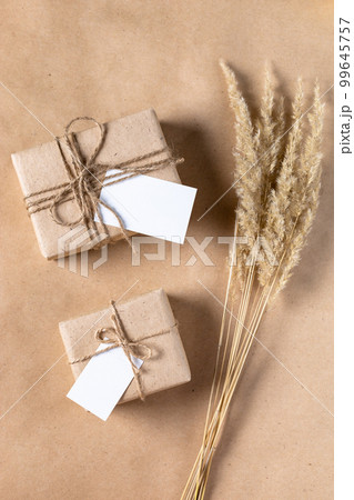 empty white gift tag mock up on craft paper box with dried spikelets decoration on natural beige background. 99645757