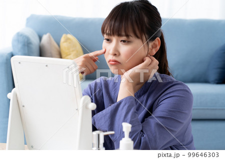 鏡で肌トラブルを確認する若い女性 鏡で肌トラブルを確認する若い女性 99646303