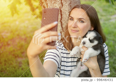 Young beautiful woman in a t-shirt and jeans with a husky puppy takes a photo 99646431