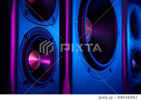 Two sound speakers and subwoofer on dark background with neon lights. Set for listening music. Audio equipment 99646982