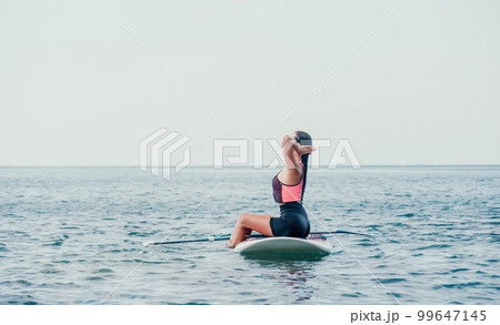 Sea woman sup. Silhouette of happy young woman in pink bikini, surfing on SUP board, confident paddling through water surface. Idyllic sunset. Active lifestyle at sea or river 99647145